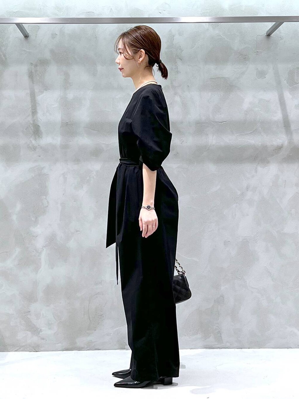 ブラウン系のハンドバッグ、ブラック系のカーディガン/ボレロ、ブラック系のつなぎ/オールインワンを着用したレディースの冬コーディネートの4枚目の写真