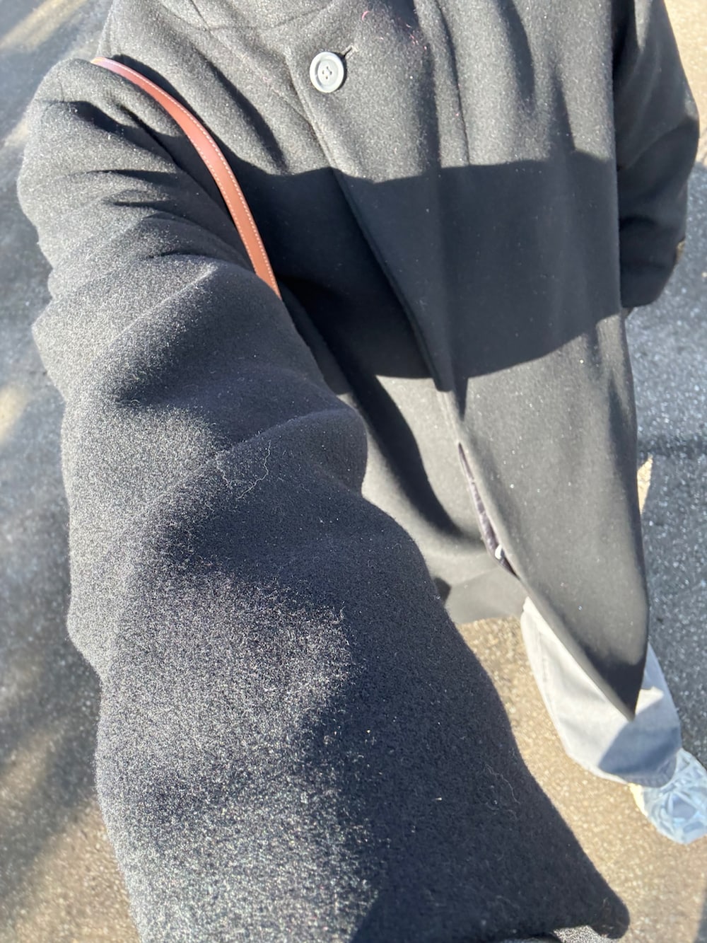 ブラック系のチェスターコート、ブラック系のデニムパンツ、ホワイト系のスニーカーを着用したメンズの冬コーディネートの2枚目の写真