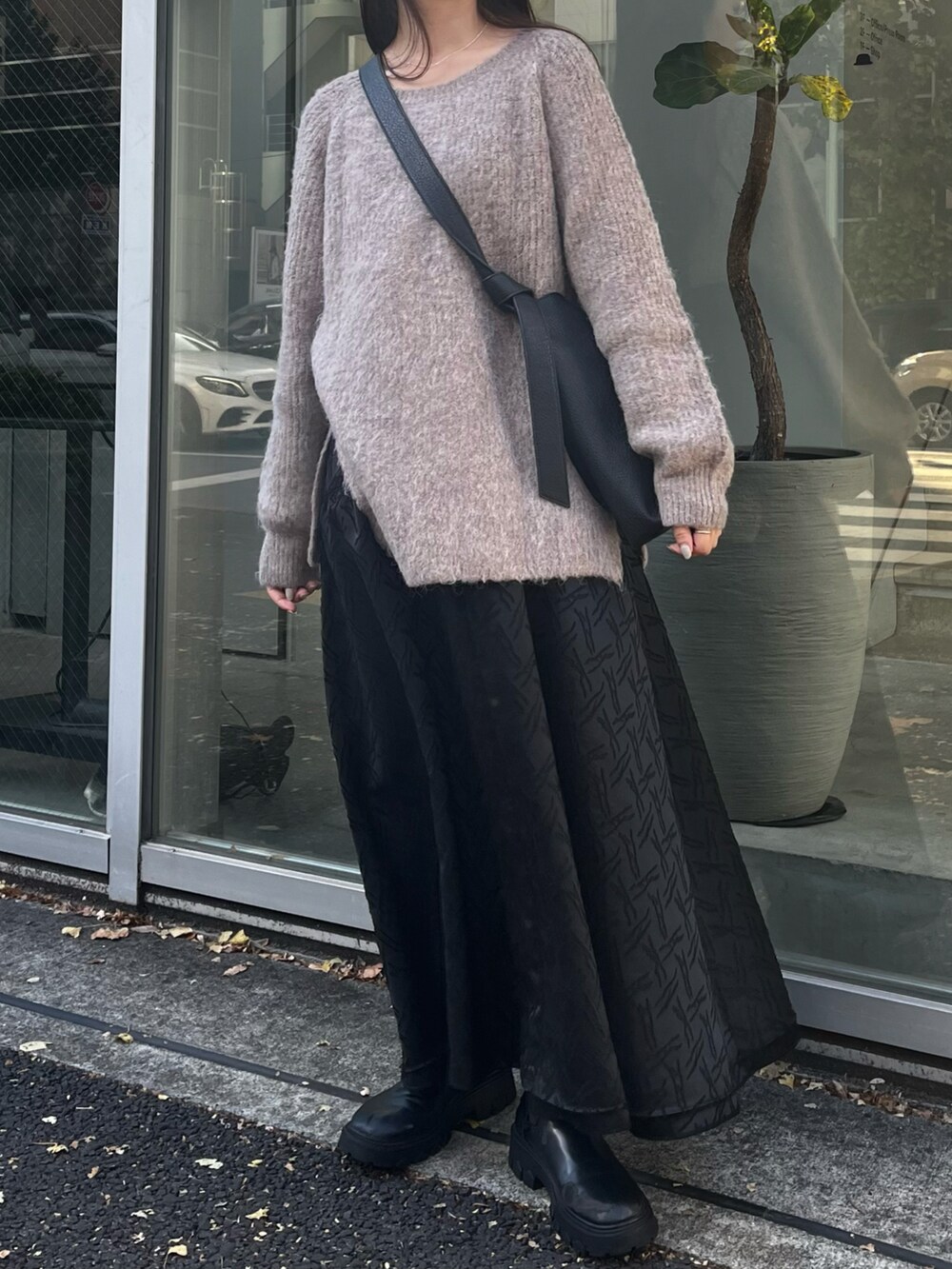 ブラック系のショルダーバッグ、ブラウン系のニット/セーター、ブラック系のワンピースを着用したレディースの秋コーディネートの3枚目の写真