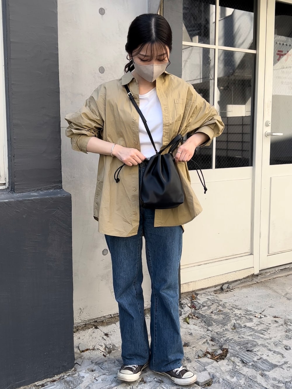 ブラック系のショルダーバッグ、ベージュ系のシャツ/ブラウス、ホワイト系のTシャツ/カットソーを着用したレディースの冬コーディネートの2枚目の写真