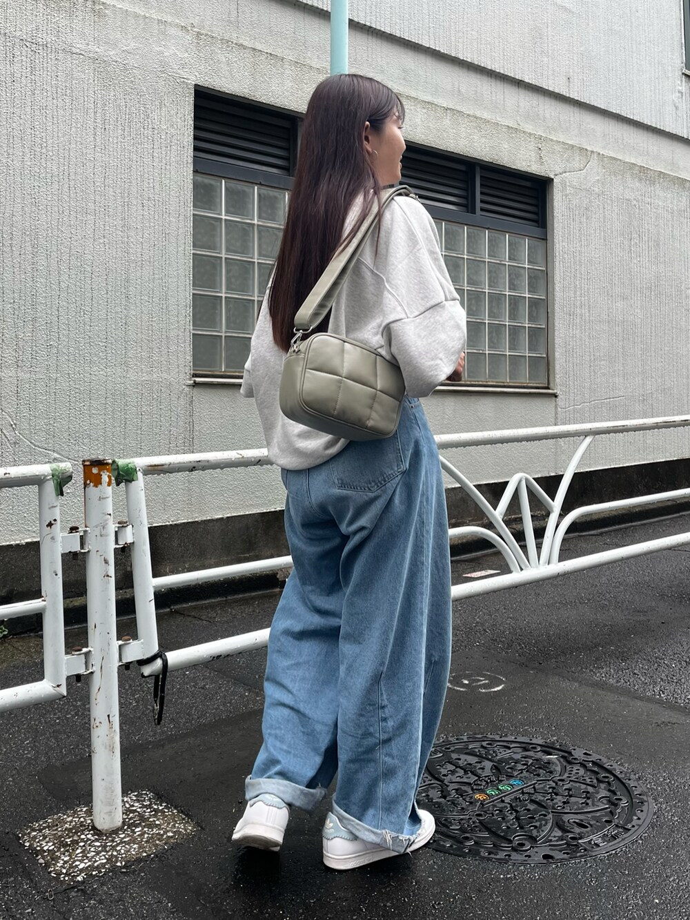グリーン系のショルダーバッグ、グレー系のスウェット、ブルー系のデニムパンツを着用したレディースの秋コーディネートの3枚目の写真