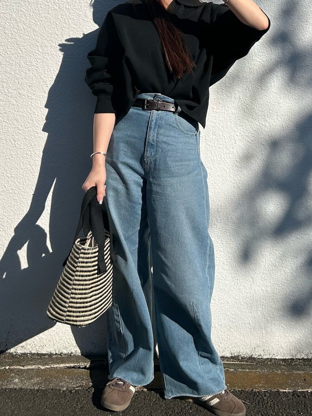 ブラック系のトートバッグ、ブラック系のニット/セーター、ブルー系のデニムパンツを着用したレディースの春コーディネートの2枚目の写真