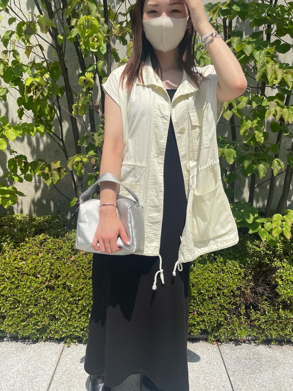 ホワイト系のベスト、ブラック系のワンピース、シルバー系のショルダーバッグを着用したレディースの夏コーディネートの3枚目の写真