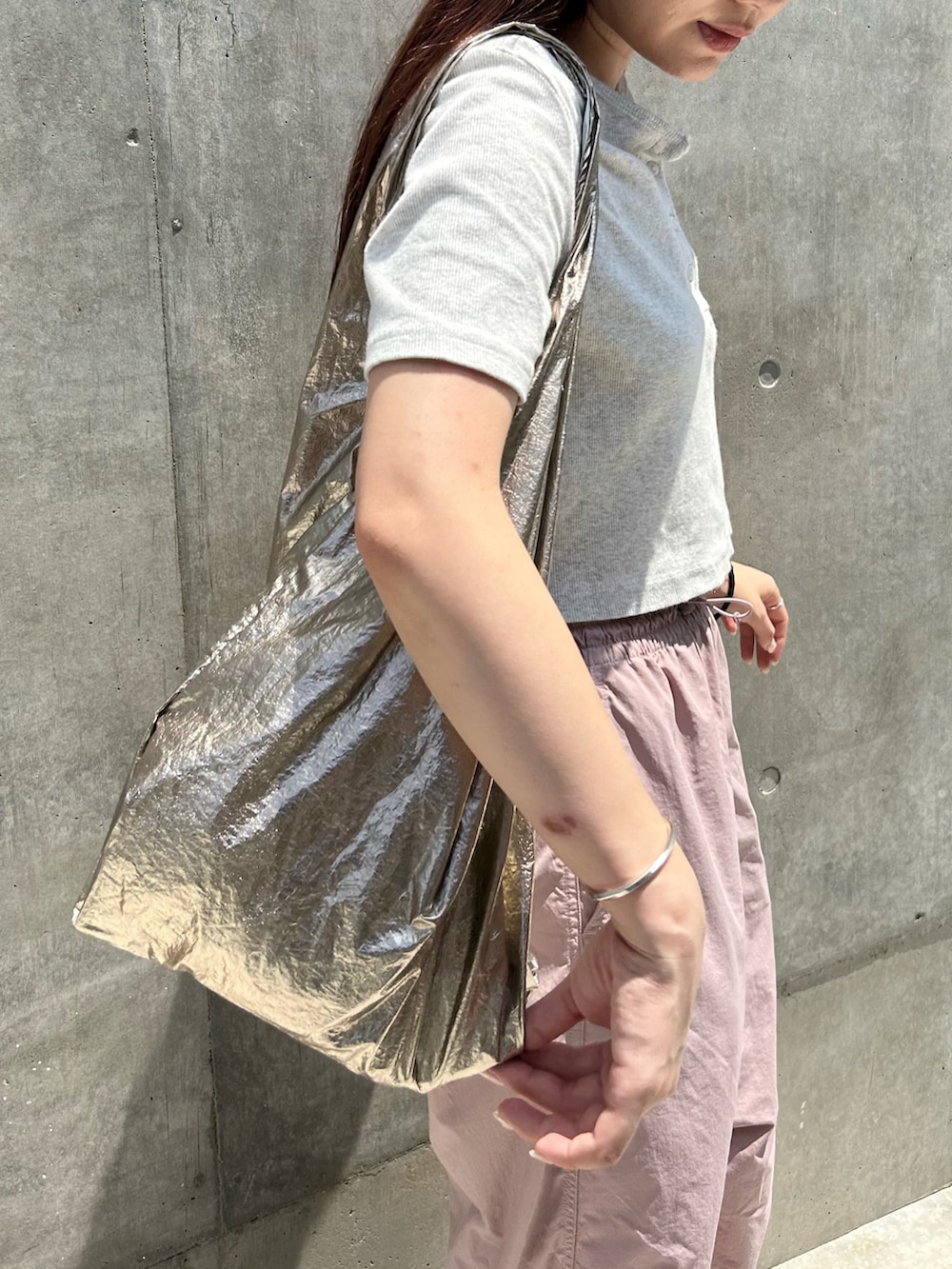 ゴールド系のエコバッグ/サブバッグ、グレー系のTシャツ/カットソー、ピンク系のパンツを着用したレディースの夏コーディネートの2枚目の写真