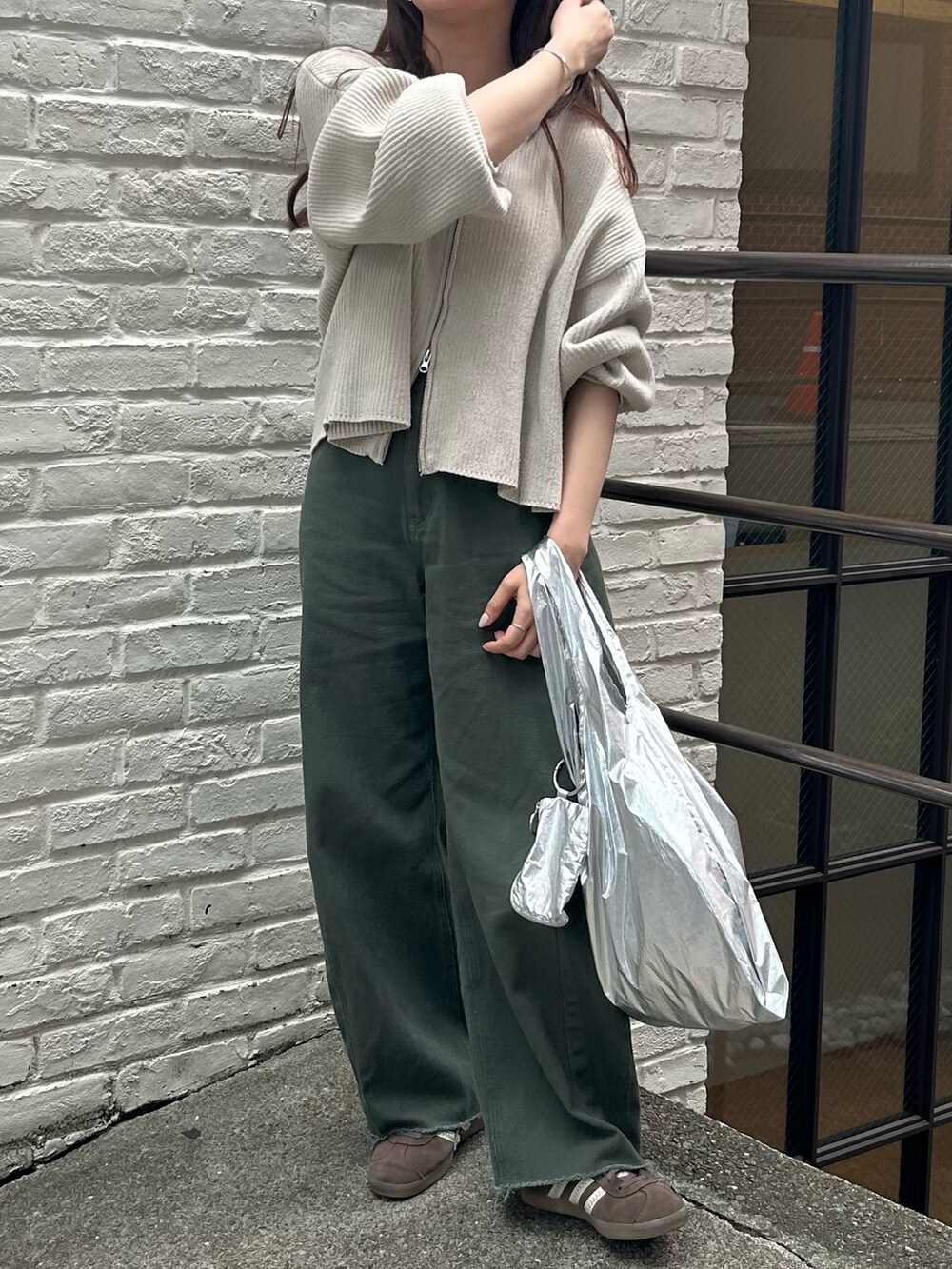 シルバー系のエコバッグ/サブバッグ、ホワイト系のニット/セーター、グリーン系のデニムパンツを着用したレディースの春コーディネートの2枚目の写真