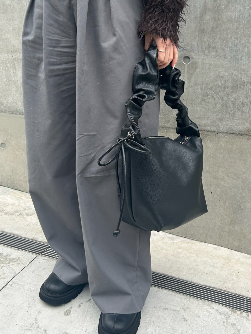 ブラック系のトートバッグ、ブラウン系のニット/セーター、グレー系のスラックスを着用したレディースの秋コーディネートの3枚目の写真