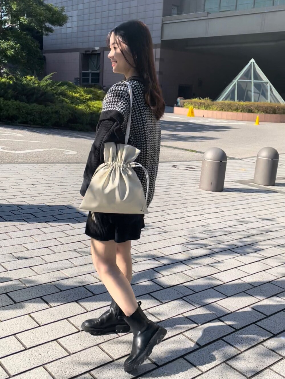 ホワイト系のトートバッグ、ブラック系のニット/セーター、ブラック系のTシャツ/カットソーを着用したレディースの秋コーディネートの2枚目の写真