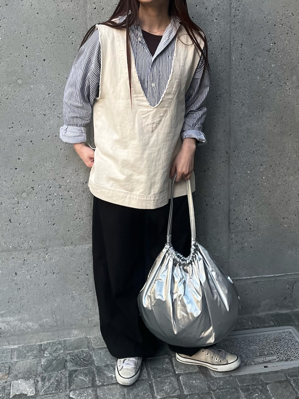 シルバー系のトートバッグ、ブラック系のシャツ/ブラウス、ホワイト系のベストを着用したレディースの春コーディネートの4枚目の写真