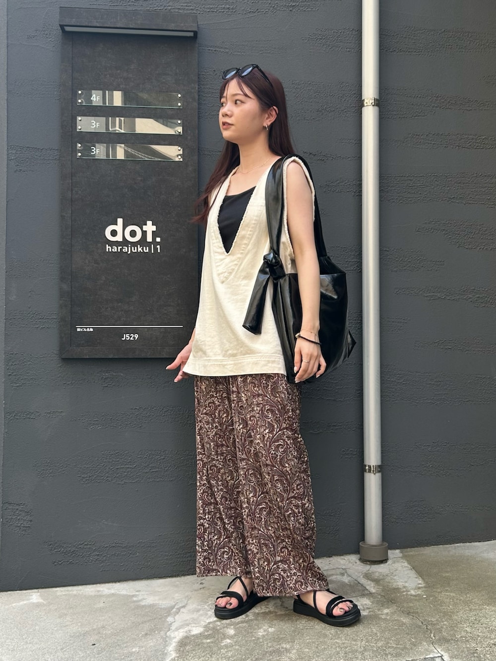 ブラック系のトートバッグ、ホワイト系のベスト、ブラウン系のその他パンツを着用したレディースの夏コーディネートの3枚目の写真