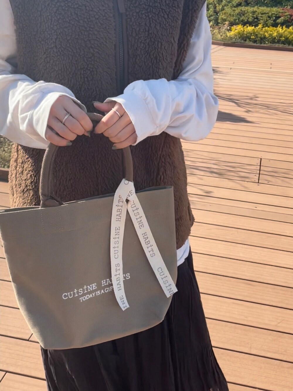 ブラウン系のジャケット/アウター、ホワイト系のTシャツ/カットソー、グリーン系のトートバッグを着用したレディースの冬コーディネートの2枚目の写真