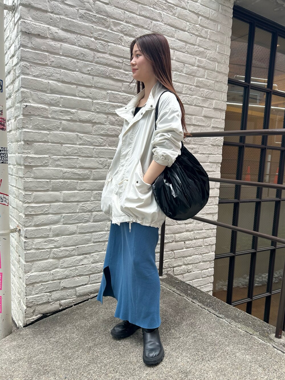 ブラック系のトートバッグ、ホワイト系のブルゾン、ブルー系のスカートを着用したレディースの春コーディネートの2枚目の写真