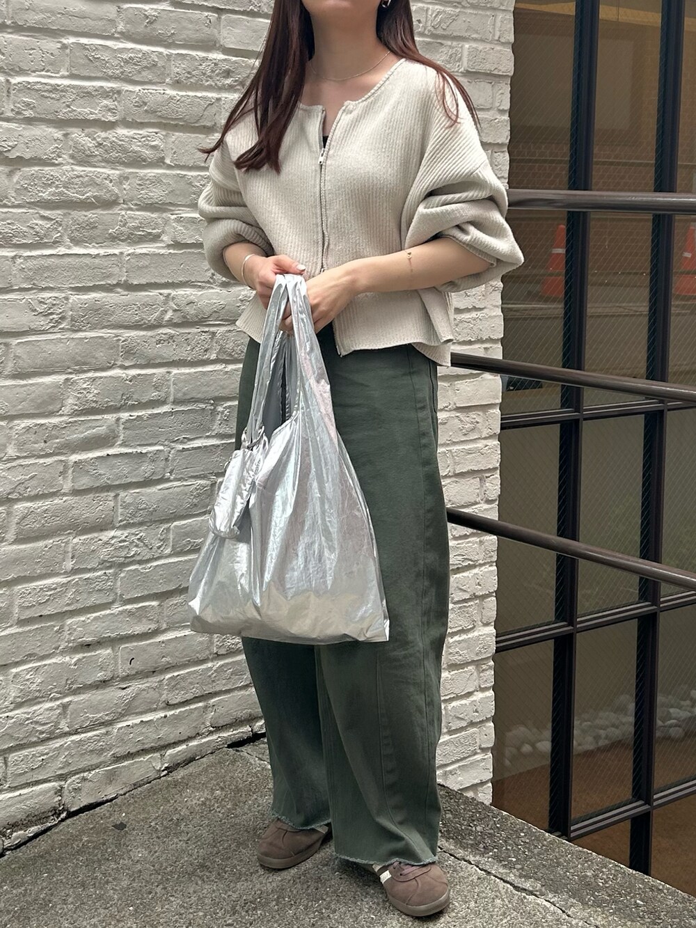 シルバー系のエコバッグ/サブバッグ、ホワイト系のニット/セーター、グリーン系のデニムパンツを着用したレディースの春コーディネートの4枚目の写真
