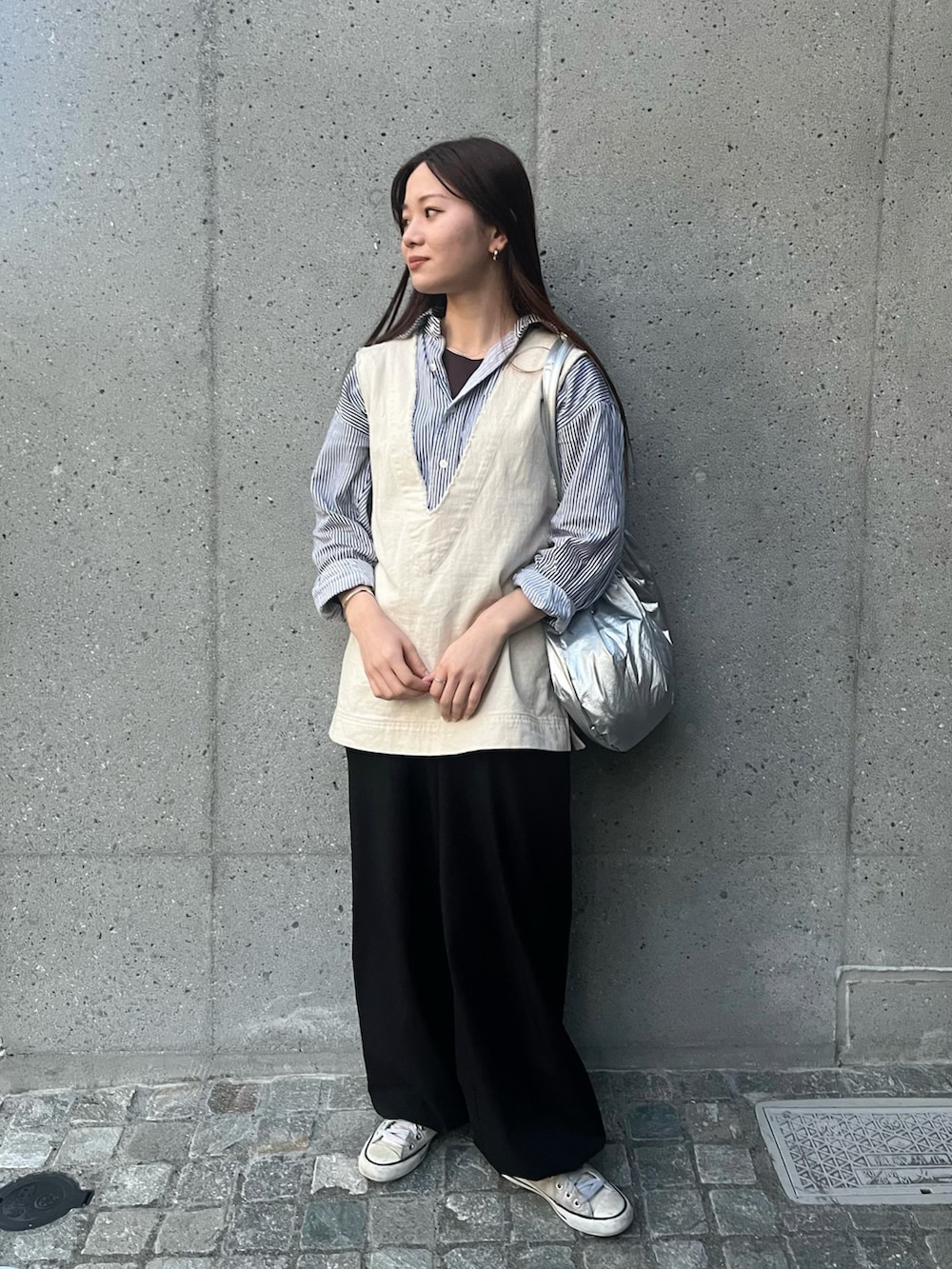 シルバー系のトートバッグ、ブラック系のシャツ/ブラウス、ホワイト系のベストを着用したレディースの春コーディネートの2枚目の写真