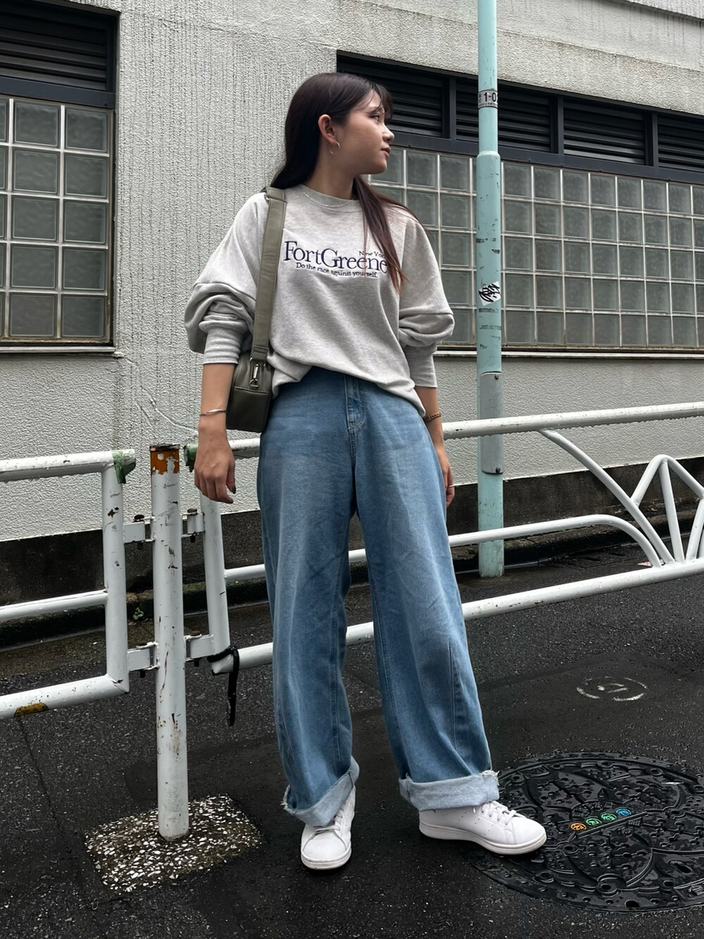 グリーン系のショルダーバッグ、グレー系のスウェット、ブルー系のデニムパンツを着用したレディースの秋コーディネートの2枚目の写真