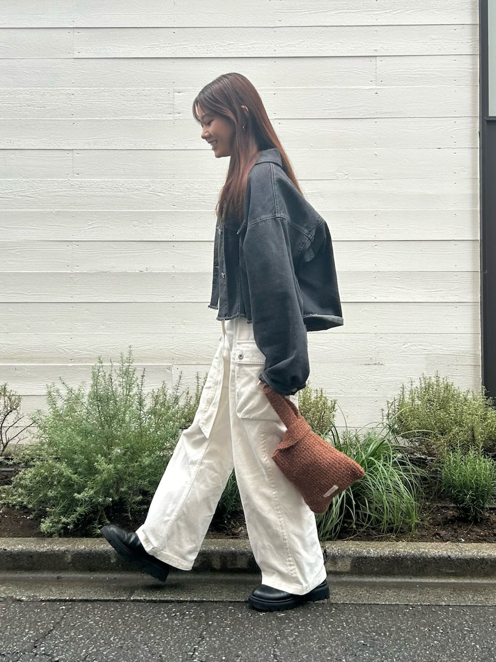ブラウン系のトートバッグ、ブラック系のデニムジャケット、ホワイト系のデニムパンツを着用したレディースの秋コーディネートの2枚目の写真