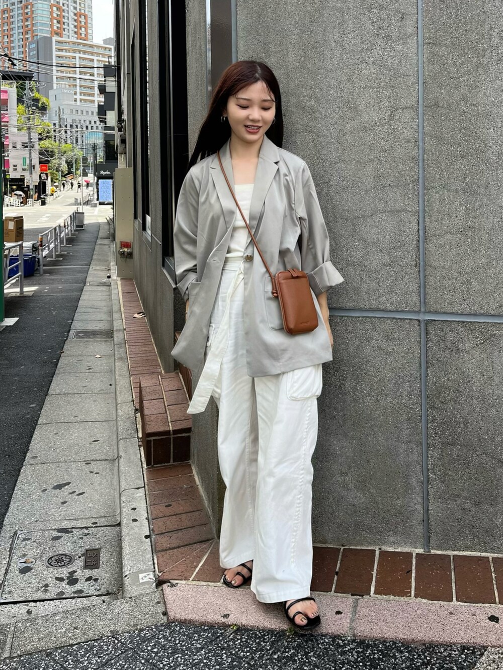 イエロー系のショルダーバッグ、グレー系のテーラードジャケット、ホワイト系のキャミソールを着用したレディースの夏コーディネートの2枚目の写真