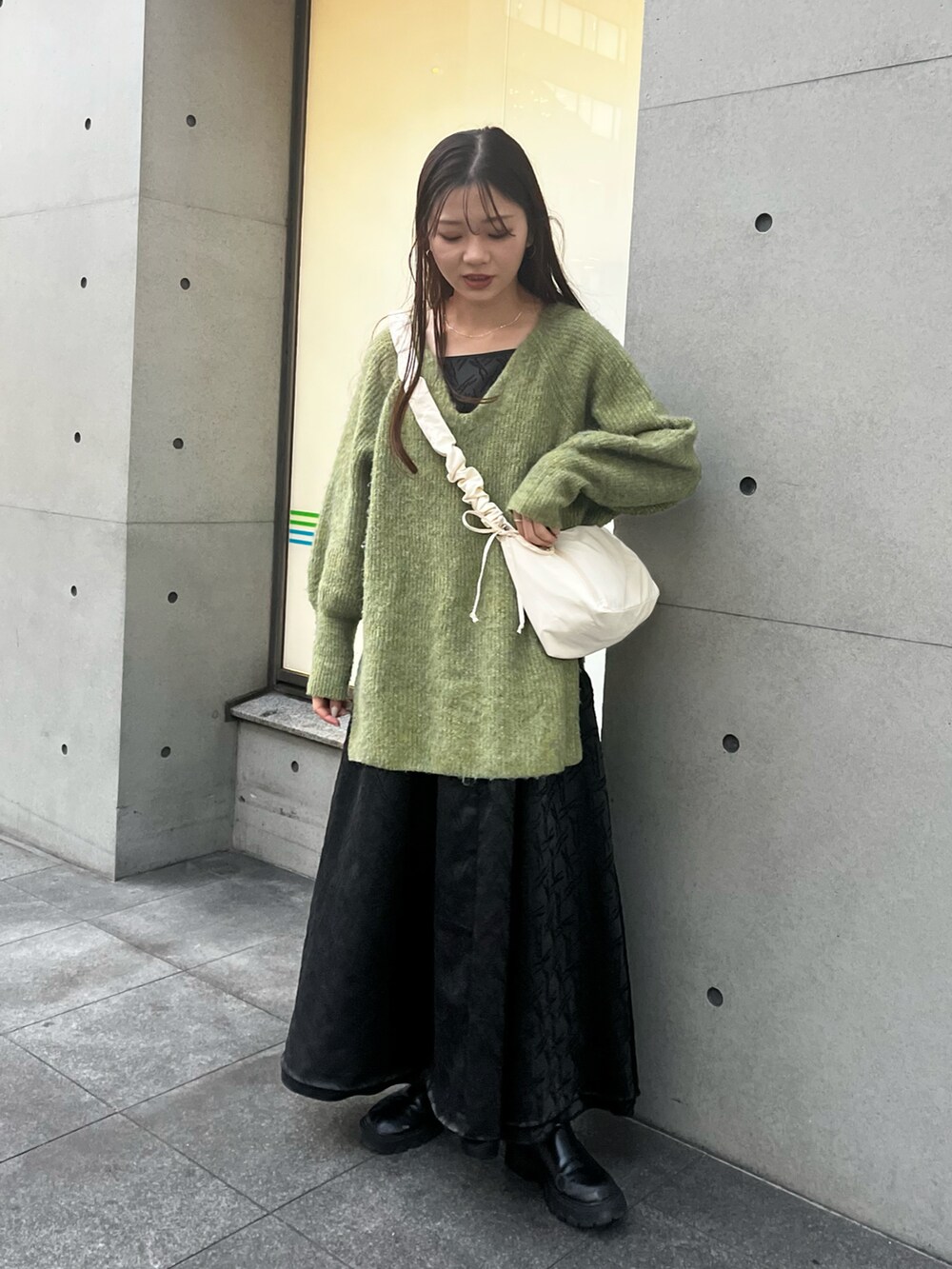 ホワイト系のショルダーバッグ、グリーン系のニット/セーター、ブラック系のワンピースを着用したレディースの冬コーディネートの2枚目の写真