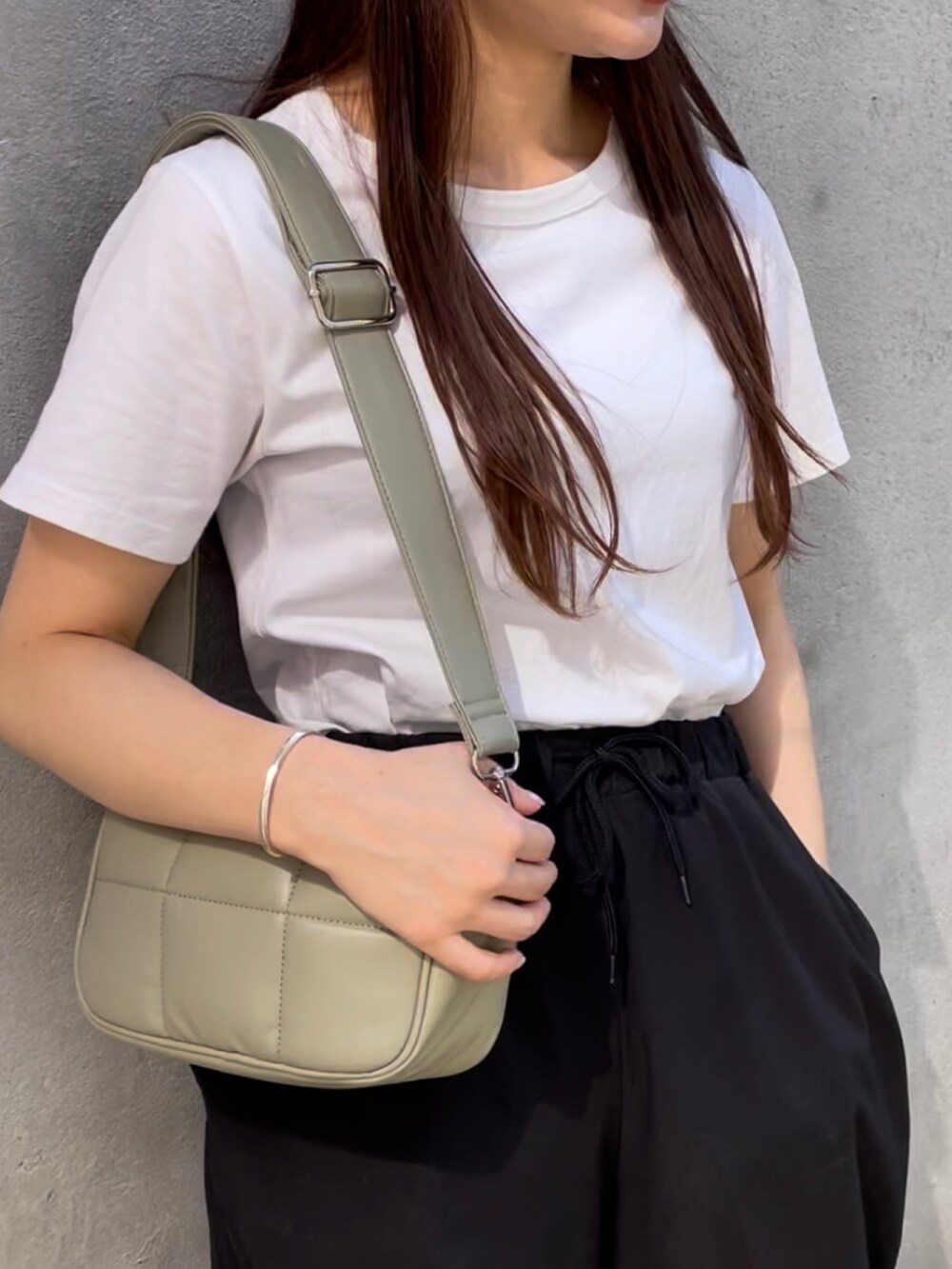 グリーン系のショルダーバッグ、ホワイト系のTシャツ/カットソー、ブラック系のカーゴパンツを着用したレディースの秋コーディネートの2枚目の写真