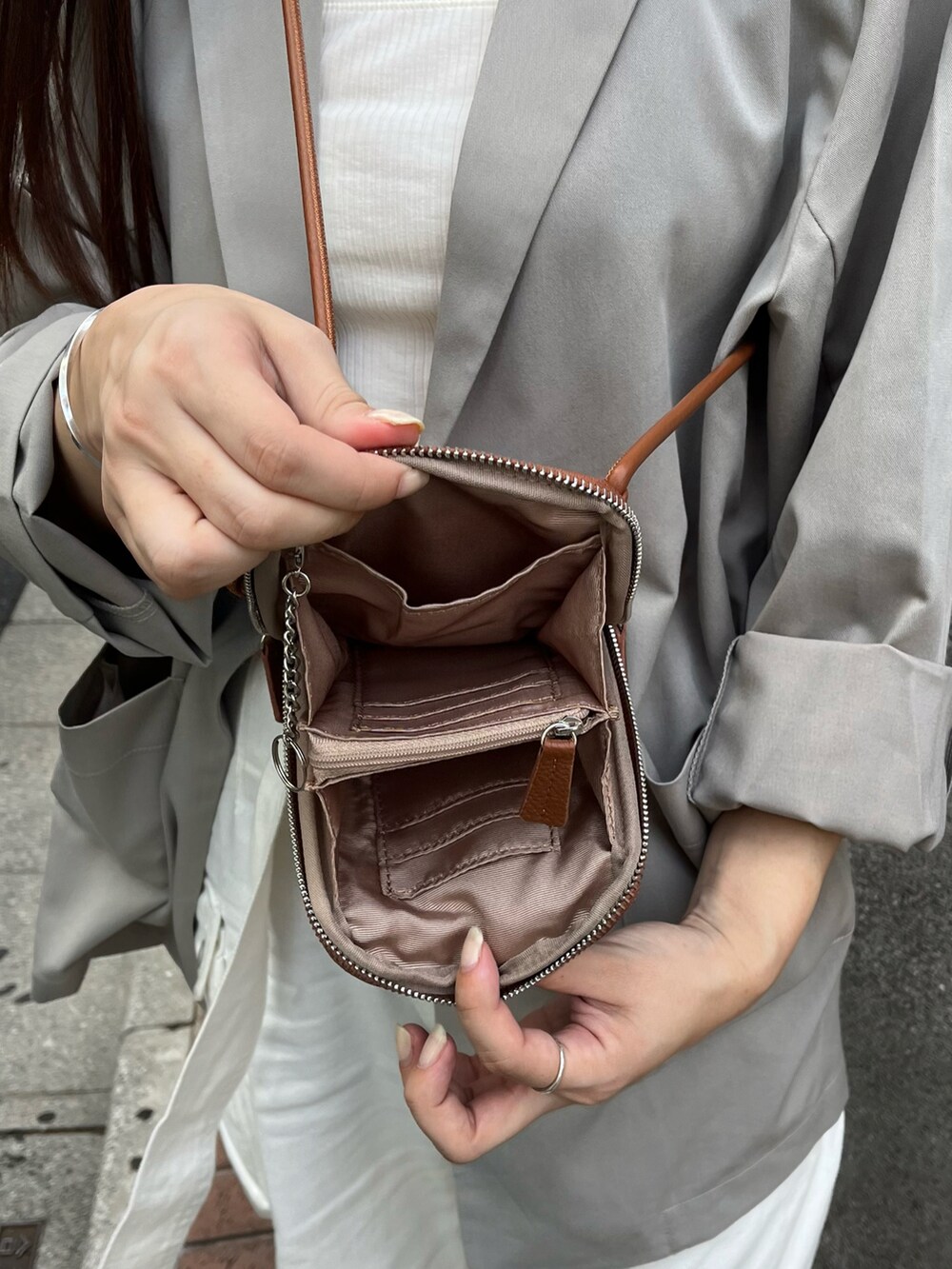 イエロー系のショルダーバッグ、グレー系のテーラードジャケット、ホワイト系のキャミソールを着用したレディースの夏コーディネートの4枚目の写真