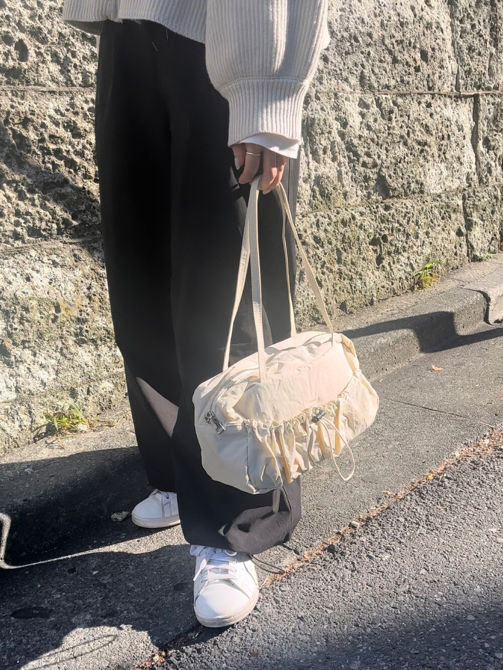 ホワイト系のトートバッグ、ホワイト系のニット/セーター、ブラック系のカーゴパンツを着用したレディースの冬コーディネートの3枚目の写真