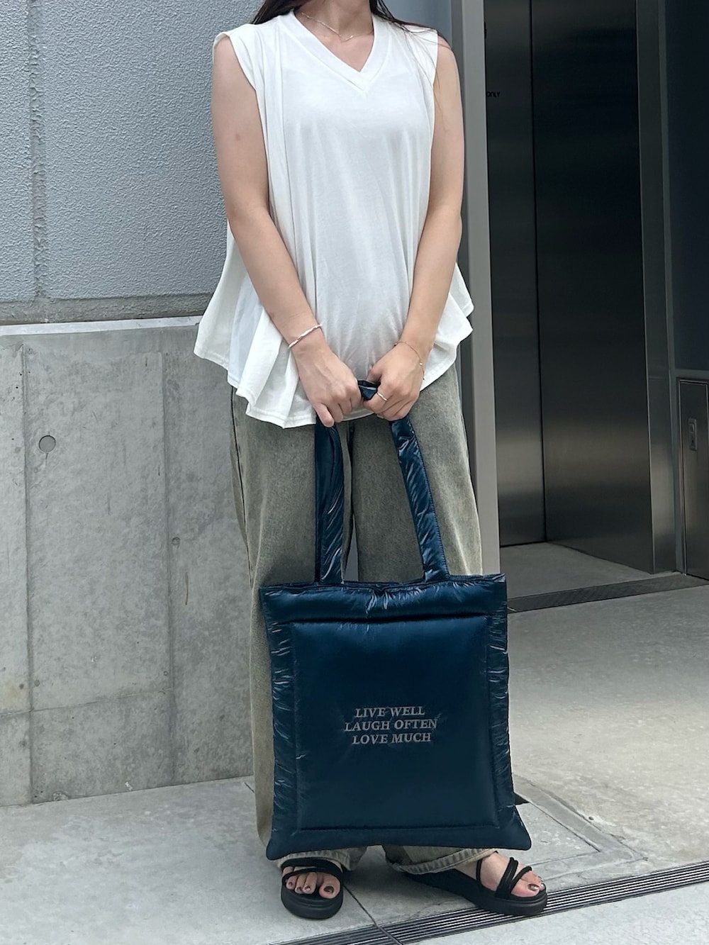 ブルー系のトートバッグ、ホワイト系のTシャツ/カットソー、ベージュ系のデニムパンツを着用したレディースの秋コーディネートの3枚目の写真