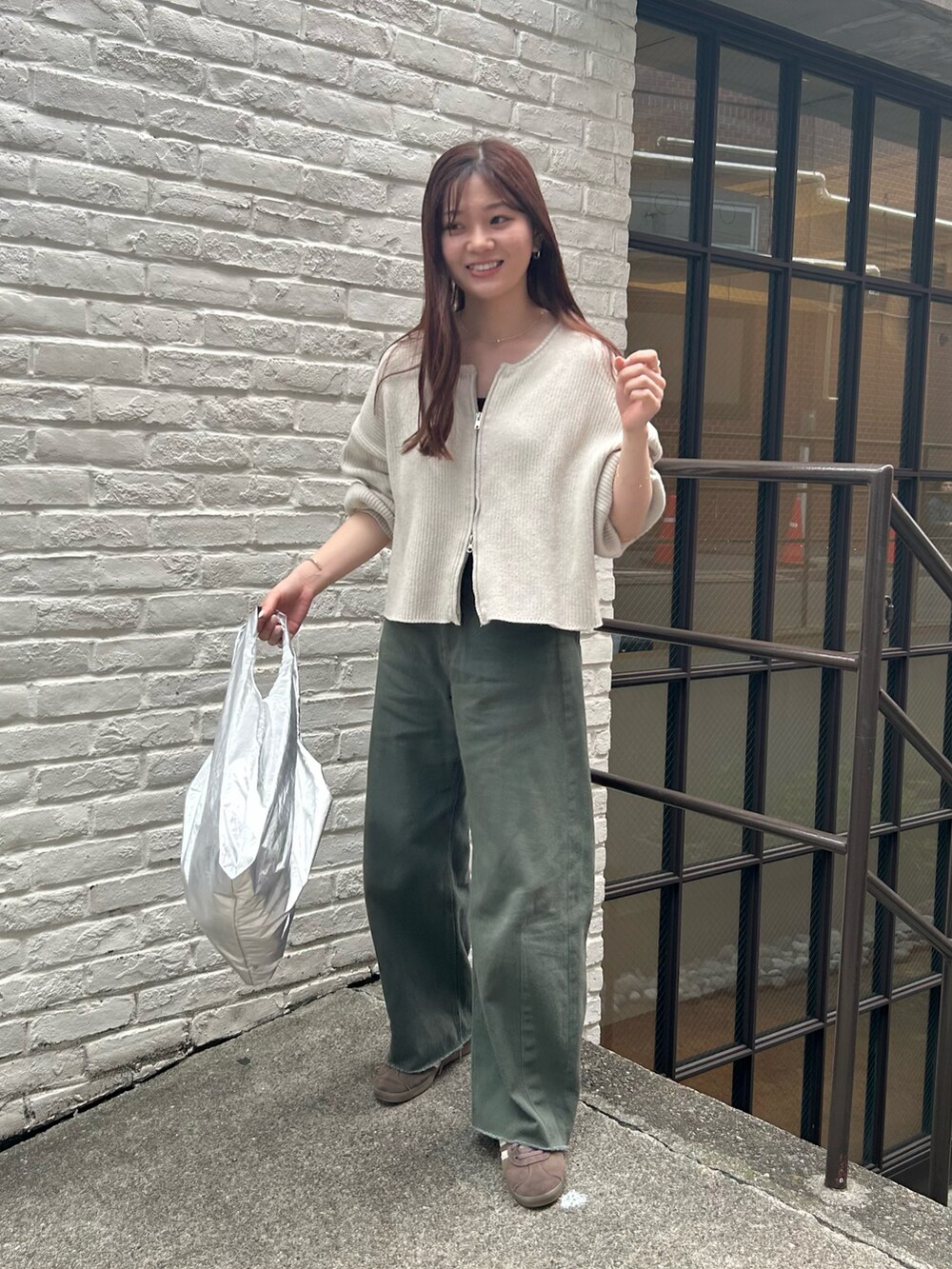 シルバー系のエコバッグ/サブバッグ、ホワイト系のニット/セーター、グリーン系のデニムパンツを着用したレディースの春コーディネートの3枚目の写真