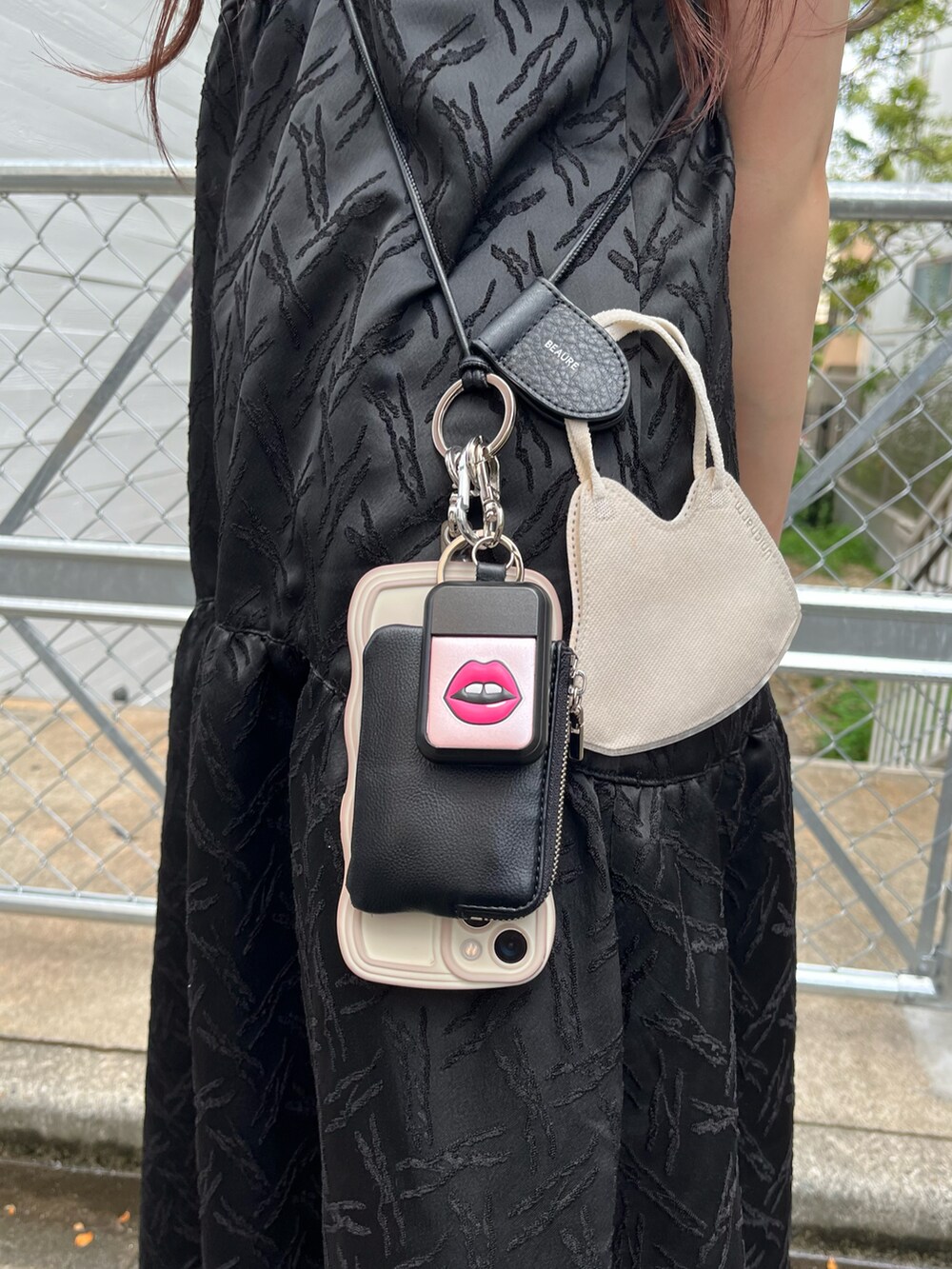 ブラック系のワンピース、ブラック系のスマホグッズ、ブラック系のパスケースを着用したレディースの夏コーディネートの2枚目の写真