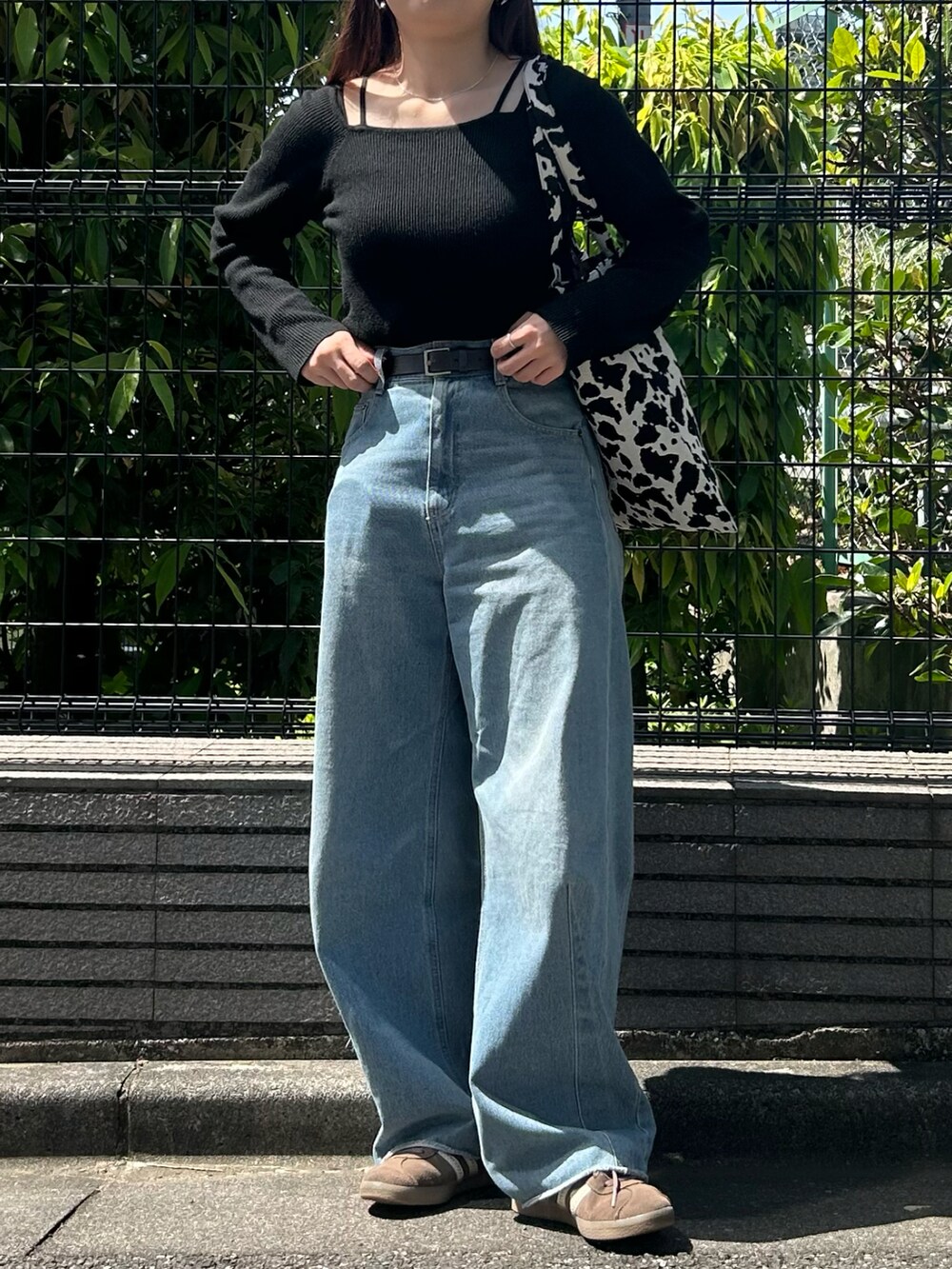 ホワイト系のトートバッグ、ブラック系のニット/セーター、ブルー系のデニムパンツを着用したレディースの春コーディネートの3枚目の写真