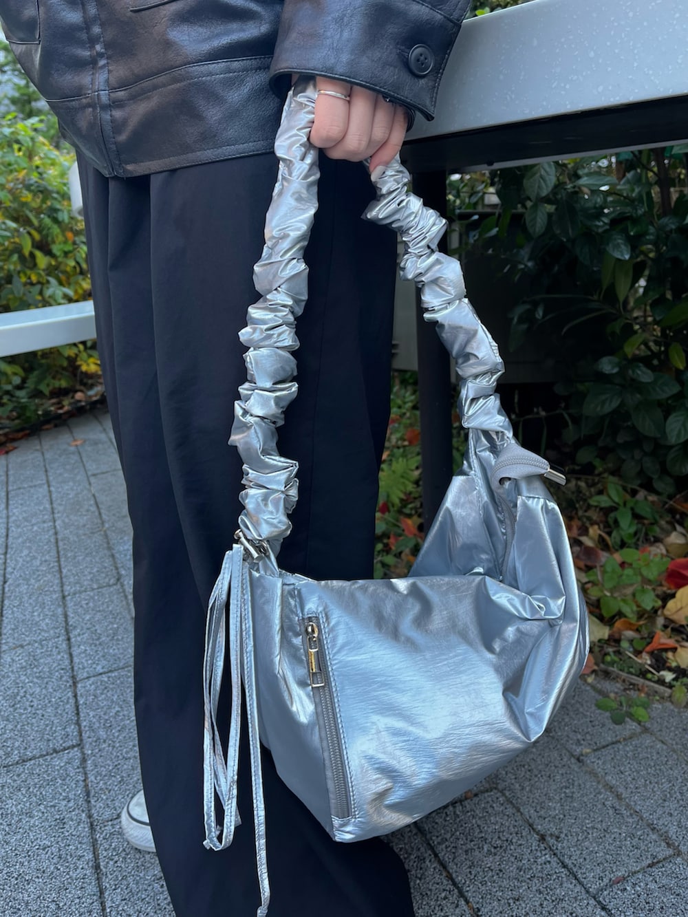 シルバー系のショルダーバッグ、ブラック系のブルゾン、ブラック系のカーゴパンツを着用したレディースの冬コーディネートの5枚目の写真