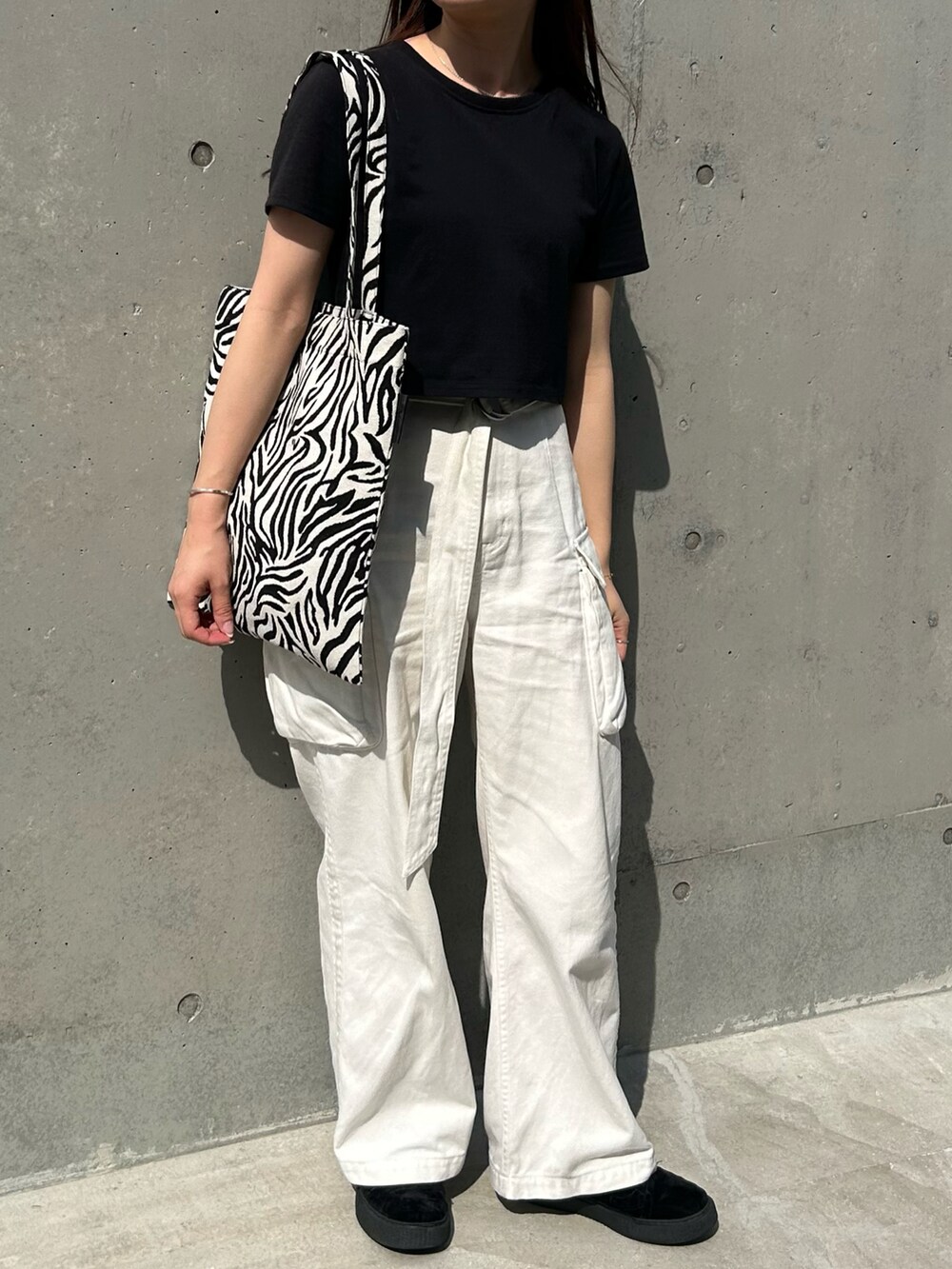 ホワイト系のトートバッグ、ブラック系のTシャツ/カットソー、ホワイト系のデニムパンツを着用したレディースの春コーディネートの2枚目の写真