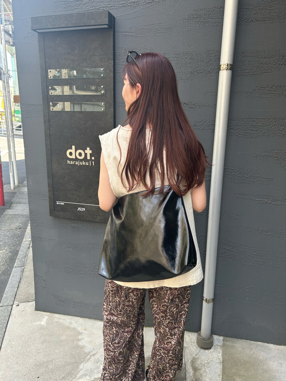 ブラック系のトートバッグ、ホワイト系のベスト、ブラウン系のその他パンツを着用したレディースの夏コーディネートの5枚目の写真