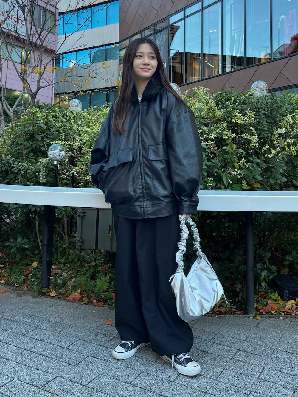 シルバー系のショルダーバッグ、ブラック系のブルゾン、ブラック系のカーゴパンツを着用したレディースの冬コーディネートの2枚目の写真