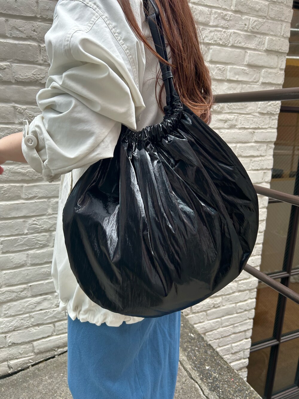 ブラック系のトートバッグ、ホワイト系のブルゾン、ブルー系のスカートを着用したレディースの春コーディネートの3枚目の写真