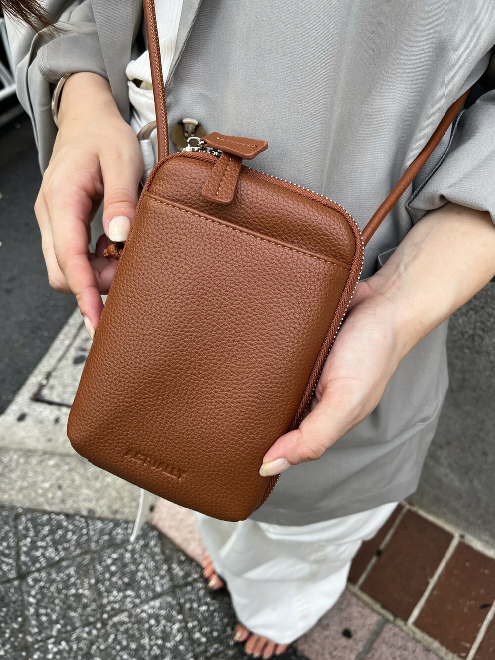 イエロー系のショルダーバッグ、グレー系のテーラードジャケット、ホワイト系のキャミソールを着用したレディースの夏コーディネートの5枚目の写真