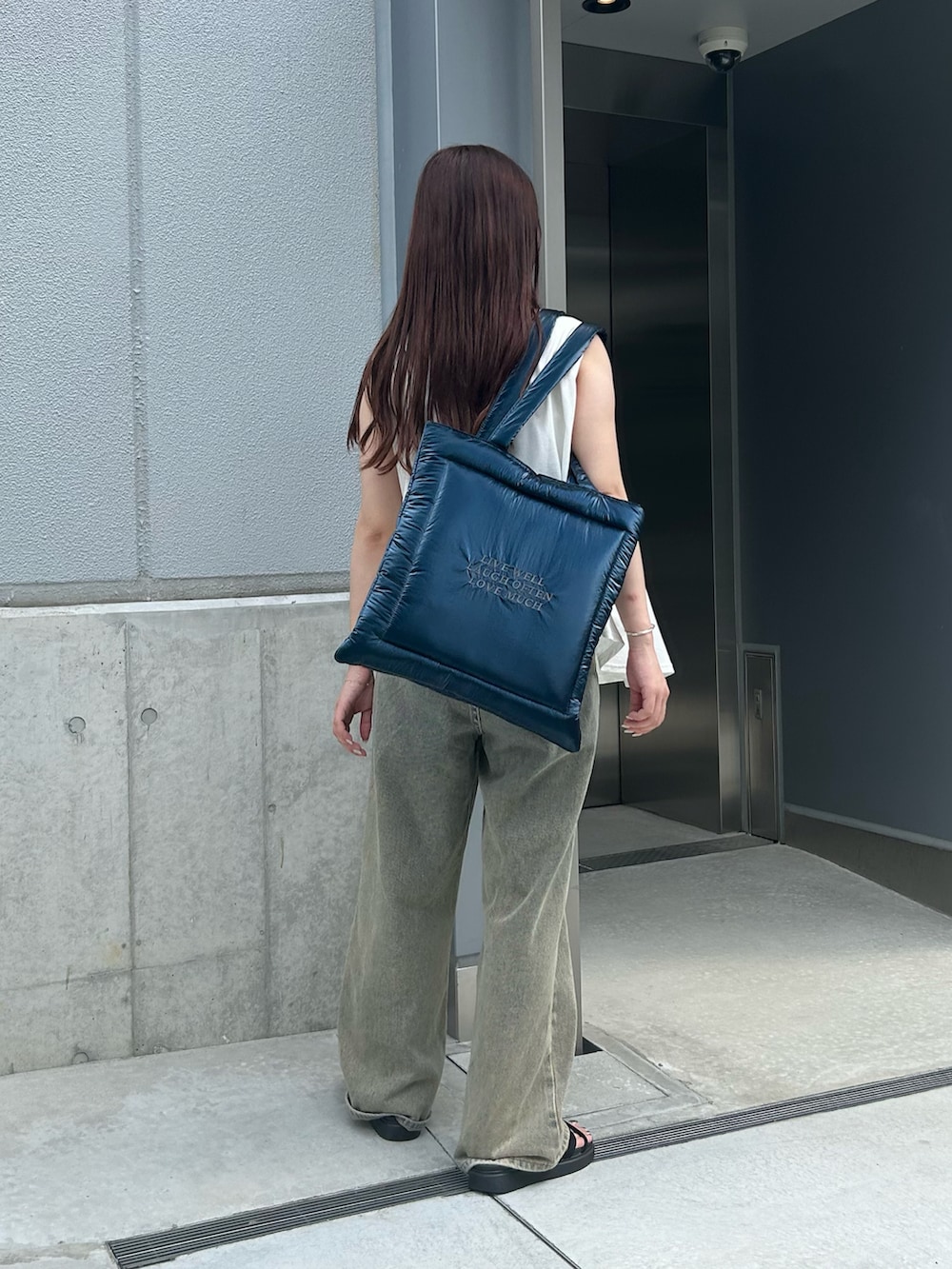 ブルー系のトートバッグ、ホワイト系のTシャツ/カットソー、ベージュ系のデニムパンツを着用したレディースの秋コーディネートの2枚目の写真