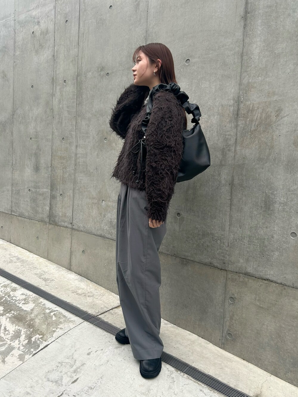 ブラック系のトートバッグ、ブラウン系のニット/セーター、グレー系のスラックスを着用したレディースの秋コーディネートの2枚目の写真