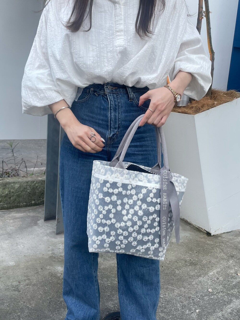 ホワイト系のトートバッグ、ホワイト系のシャツ/ブラウス、ブルー系のデニムパンツを着用したレディースの春コーディネートの3枚目の写真