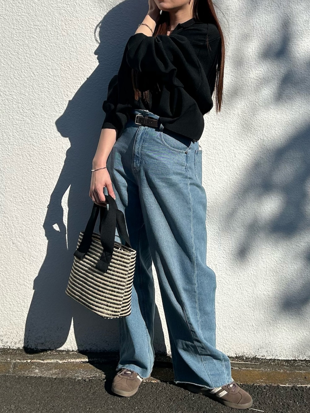 ブラック系のトートバッグ、ブラック系のニット/セーター、ブルー系のデニムパンツを着用したレディースの春コーディネートの3枚目の写真