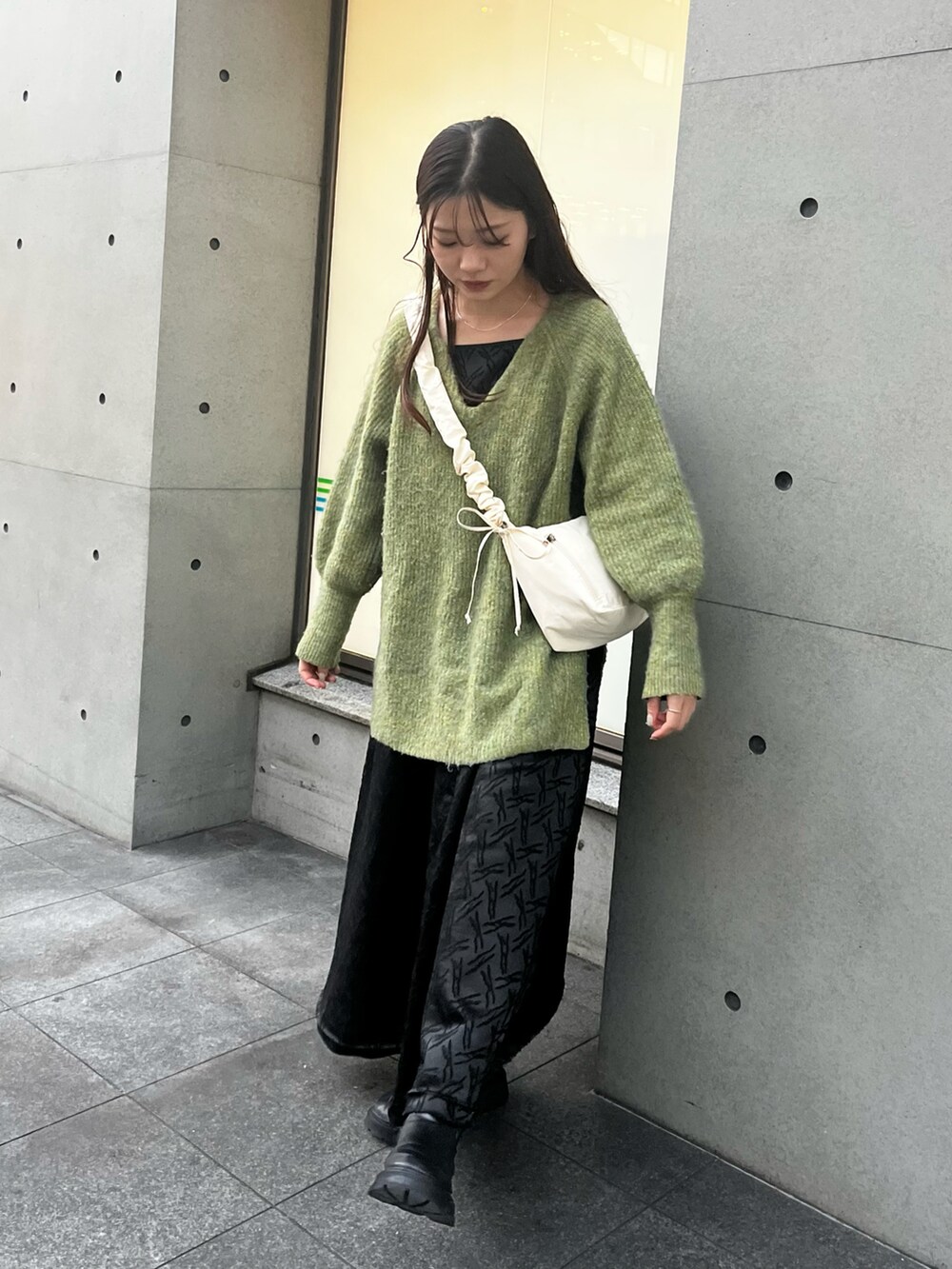ホワイト系のショルダーバッグ、グリーン系のニット/セーター、ブラック系のワンピースを着用したレディースの冬コーディネートの3枚目の写真