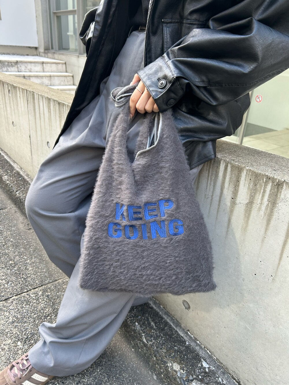 グレー系のトートバッグ、ブラック系のニット/セーター、ブラック系のブルゾンを着用したレディースの秋コーディネートの3枚目の写真
