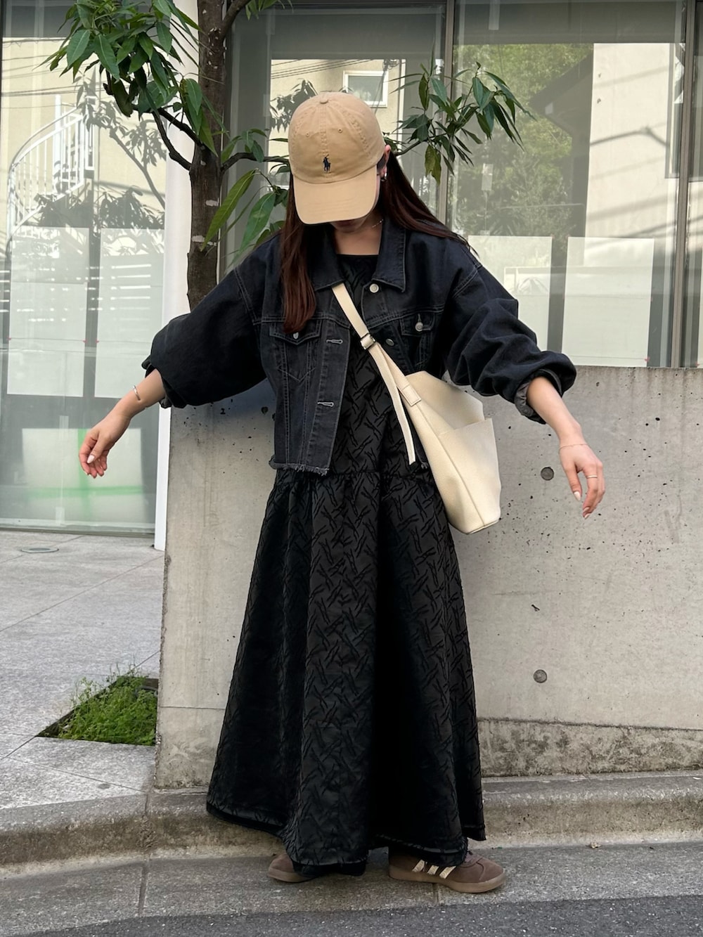 ホワイト系のショルダーバッグ、ブラック系のデニムジャケット、ブラック系のワンピースを着用したレディースの春コーディネートの2枚目の写真