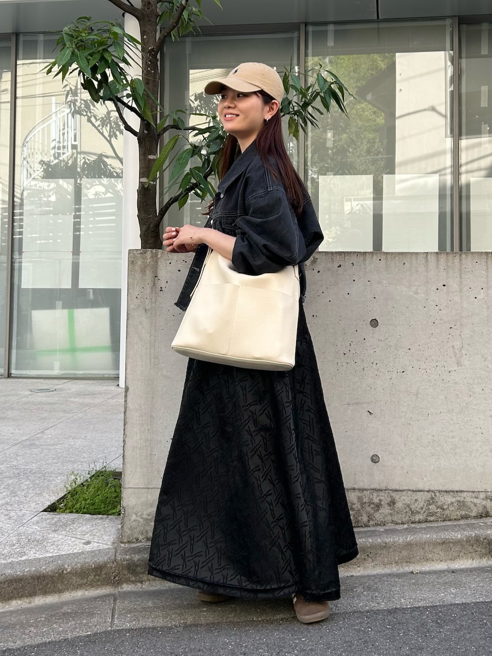 ホワイト系のショルダーバッグ、ブラック系のデニムジャケット、ブラック系のワンピースを着用したレディースの春コーディネートの3枚目の写真