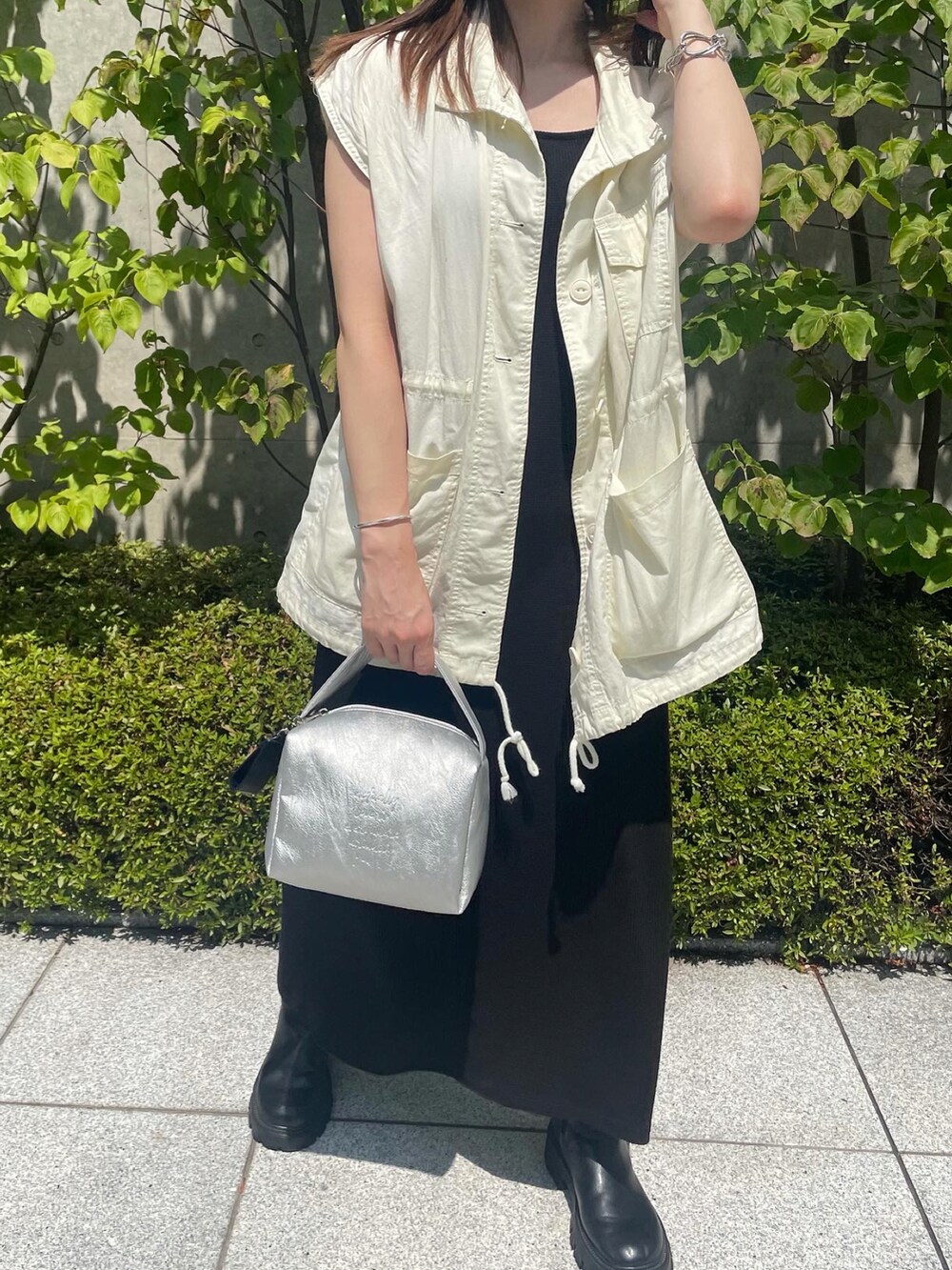 ホワイト系のベスト、ブラック系のワンピース、シルバー系のショルダーバッグを着用したレディースの夏コーディネートの2枚目の写真