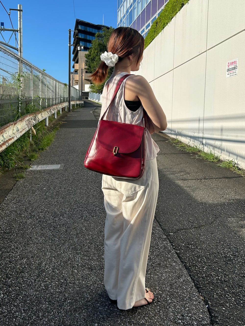 レッド系のトートバッグを着用したレディースの夏コーディネートの2枚目の写真