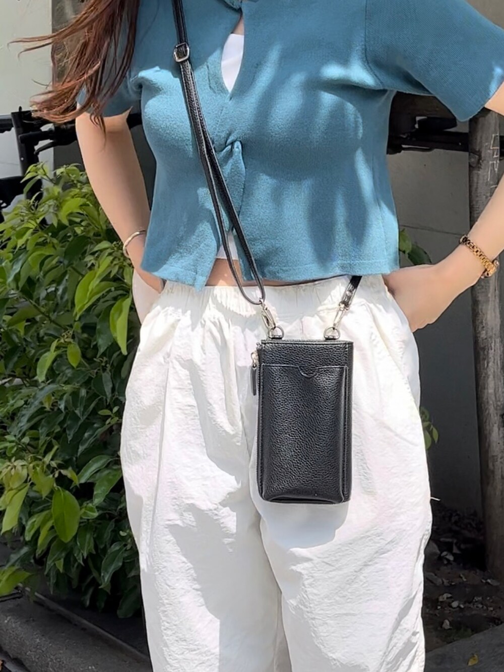 ブラック系のショルダーバッグ、グリーン系のニット/セーター、ホワイト系のキャミソールを着用したレディースの夏コーディネートの3枚目の写真