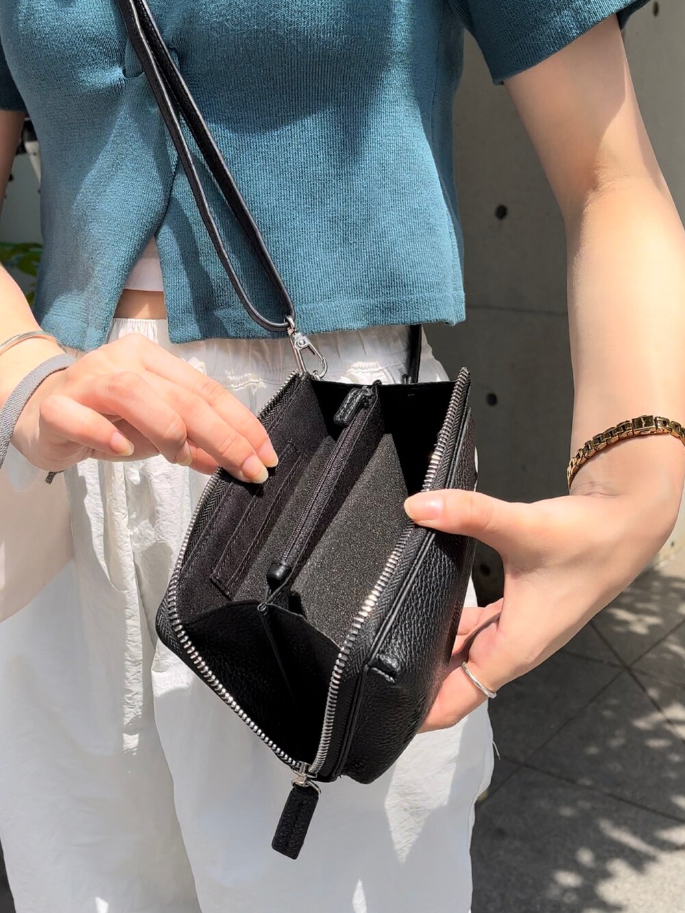 ブラック系のショルダーバッグ、グリーン系のニット/セーター、ホワイト系のキャミソールを着用したレディースの夏コーディネートの2枚目の写真