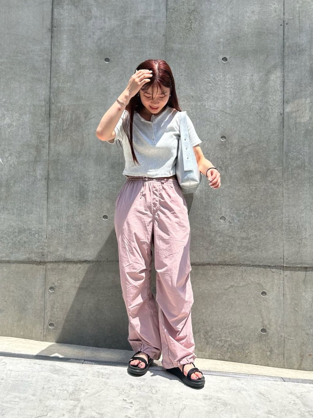 シルバー系のショルダーバッグ、グレー系のTシャツ/カットソー、ピンク系のパンツを着用したレディースの夏コーディネートの2枚目の写真