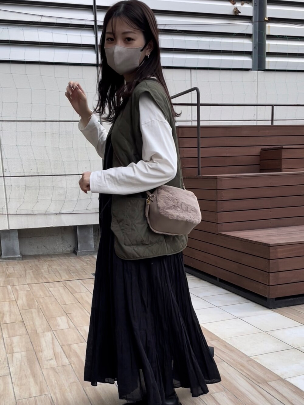 グレー系のショルダーバッグ、グリーン系のベスト、ホワイト系のTシャツ/カットソーを着用したレディースの秋コーディネートの2枚目の写真