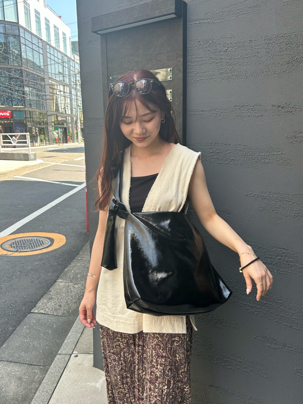 ブラック系のトートバッグ、ホワイト系のベスト、ブラウン系のその他パンツを着用したレディースの夏コーディネートの4枚目の写真