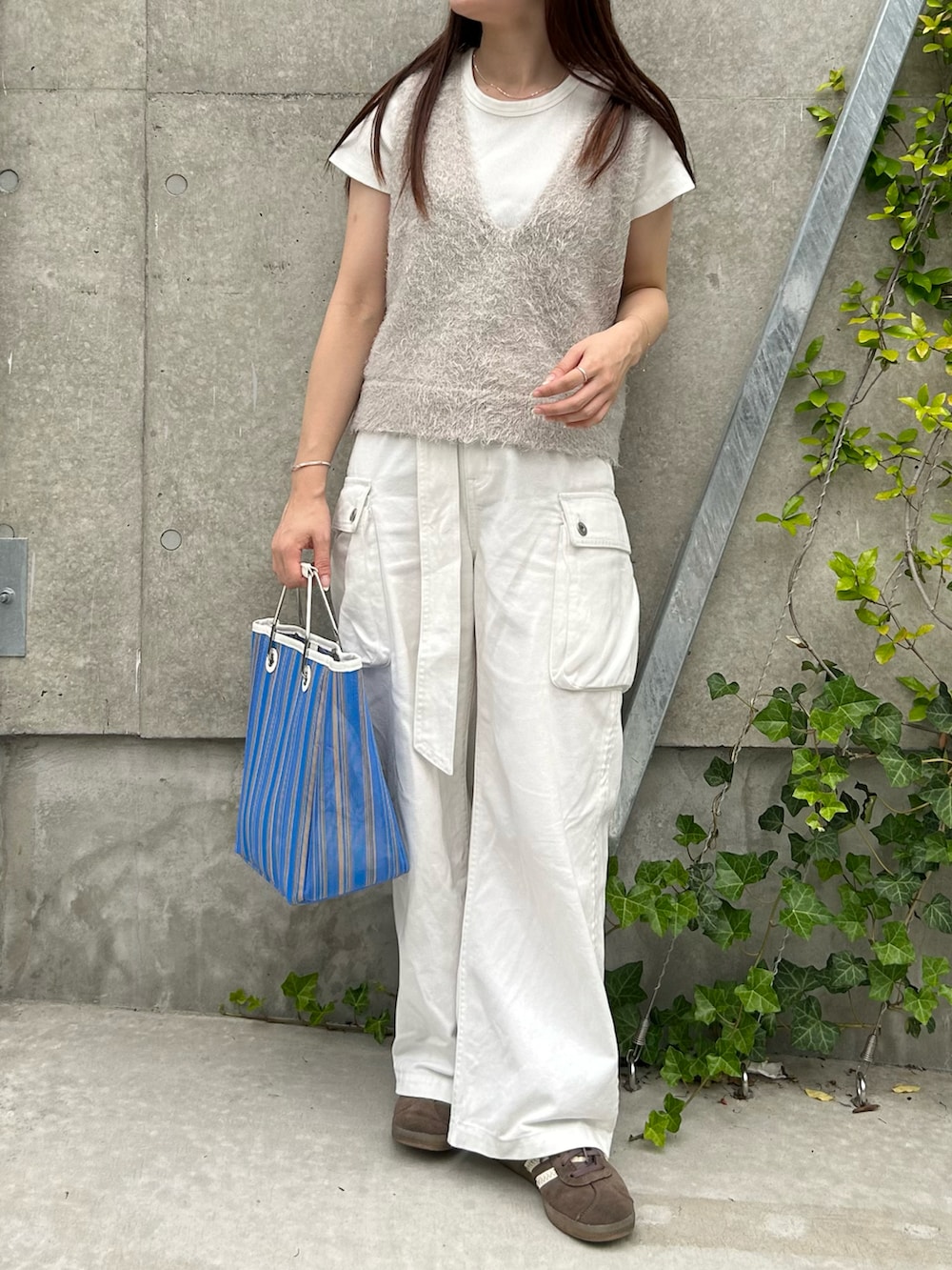 ブルー系のトートバッグ、グレー系のベスト、ホワイト系のTシャツ/カットソーを着用したレディースの夏コーディネートの2枚目の写真